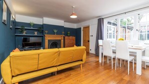 A living room with a sofa, a TV, a fireplace, and a dining area with chairs and a table.