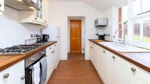 A kitchen with white cabinets, a wooden countertop, a stove, and a window.