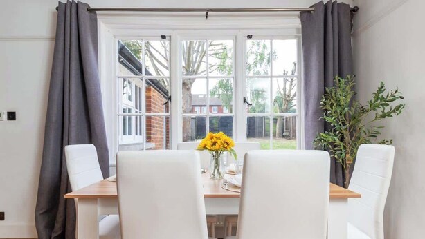 A dining area with a table, chairs, and a window with curtains.