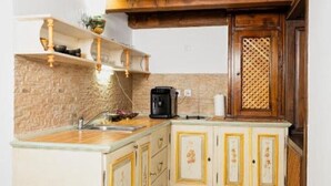 A kitchen with a brick backsplash, wooden cabinets, and a coffee maker. - Apartament 1 (Timișoara)