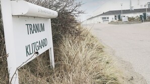 Ein Schild mit der Aufschrift 'TRANUM' und 'KLITGAARD', im Hintergrund ein Gebäude.