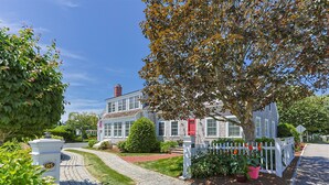 A two-story house with a red door, a white picket fence, and a paved driveway. - Walk to Famous Chatham Lighthouse Beach (Chatham)