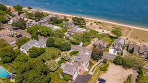 An aerial view of a coastal residential area with houses, a beach, and a clear view of the ocean. - Walk to Famous Chatham Lighthouse Beach (Chatham)