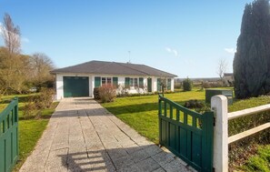 A single-story building with a garage, a paved driveway, and a green gate. - Cozy home in RUMINGHEM with WiFi (RUMINGHEM)