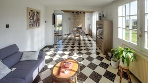 A living room with a checkered floor, a sofa, a coffee table, a fireplace, and a view through large windows. - Cozy home in RUMINGHEM with WiFi (RUMINGHEM)