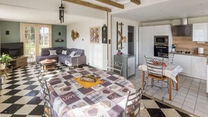 A living room with a sofa, a dining table, and a kitchen area with appliances. - Cozy home in RUMINGHEM with WiFi (RUMINGHEM)