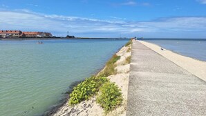 A coastal walkway with a sandy path, a grassy area with bushes, and a calm sea. - Cozy home in RUMINGHEM with WiFi (RUMINGHEM)