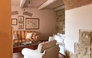 Una sala de estar con sofá, sillones, una mesa de centro y cuadros en la pared.