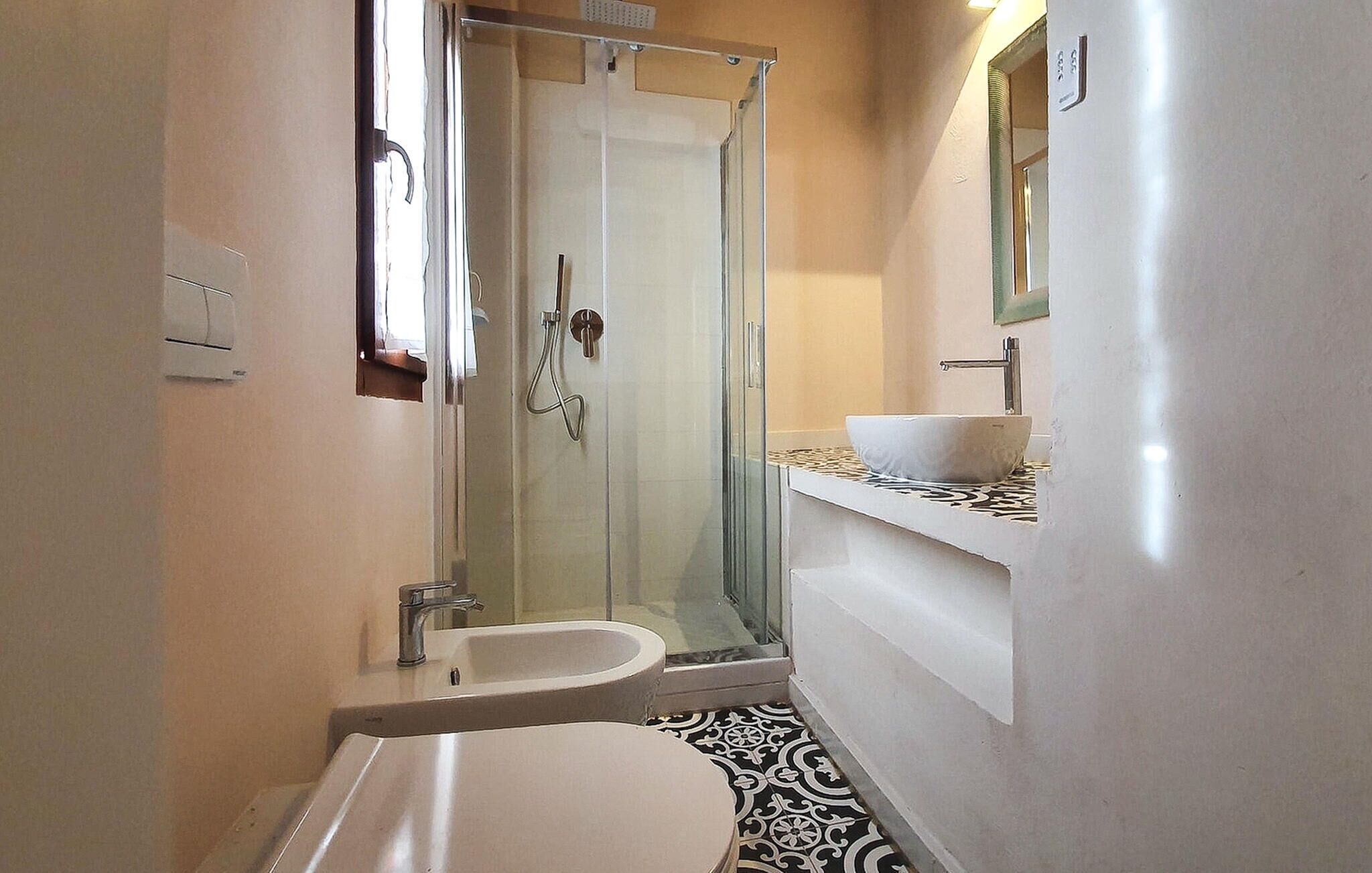 Un baño con ducha de vidrio, inodoro y lavamanos con espejo.