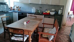 Una cocina con salpicadero de azulejos, una mesa de comedor con sillas y piso de ladrillo.