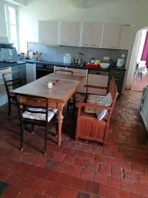 A kitchen with a tiled backsplash, a dining table with chairs, and a brick floor. - Enter the wonderful world of nature and the stars of Morvan (Arleuf)