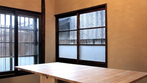 Una stanza con un tavolo di legno, un lampadario, una finestra con pannelli di vetro satinato e un condizionatore d'aria.