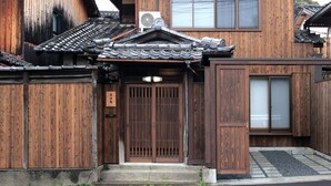 Un edificio tradizionale in legno con tetto in tegole, una porta in legno e un piccolo condizionatore d'aria.