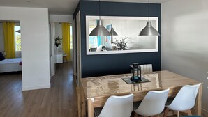 Ein stilvoller Essbereich mit einem Holztisch, weißen Stühlen und Pendelleuchten.