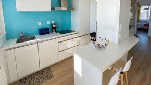 Eine moderne Küche mit blauer Akzentwand, weißen Schränken, einer Kaffeemaschine und einer Bar mit Hockern.