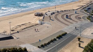 Eine Küstenstraße mit Strand, einem Steg und einem Parkplatz.