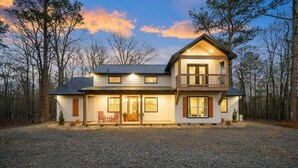 A two-story house with a front porch, a balcony on the upper floor, and a gravel driveway. - Pickleball, Pool, Splash Fountain ,Clubhouse , Walking Trails , Basketball (Broken Bow)