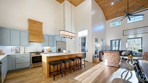 A spacious kitchen with a central island, wooden ceiling, and large windows. - Pickleball, Pool, Splash Fountain ,Clubhouse , Walking Trails , Basketball (Broken Bow)