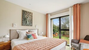 A hotel room with a large bed, a view of the outdoors, a peacock painting, and a cozy seating area. - MH Hôtel & Spa (Arradon)