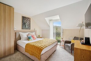 A bedroom with a bed, a desk, a chair, a balcony, and a painting on the wall. - MH Hôtel & Spa (Arradon)
