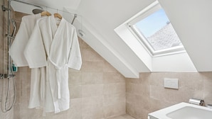 A modern bathroom with a skylight, a bathtub, and a shower area. - MH Hôtel & Spa (Arradon)