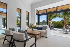 Ein modernes Wohnzimmer mit Blick auf einen Pool, großen Fenstern und einer Terrasse.