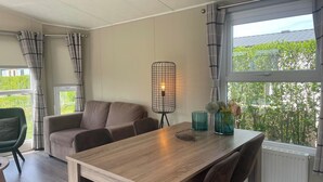 Una sala moderna con una mesa de comedor de madera, un sofá y una lámpara de pie.