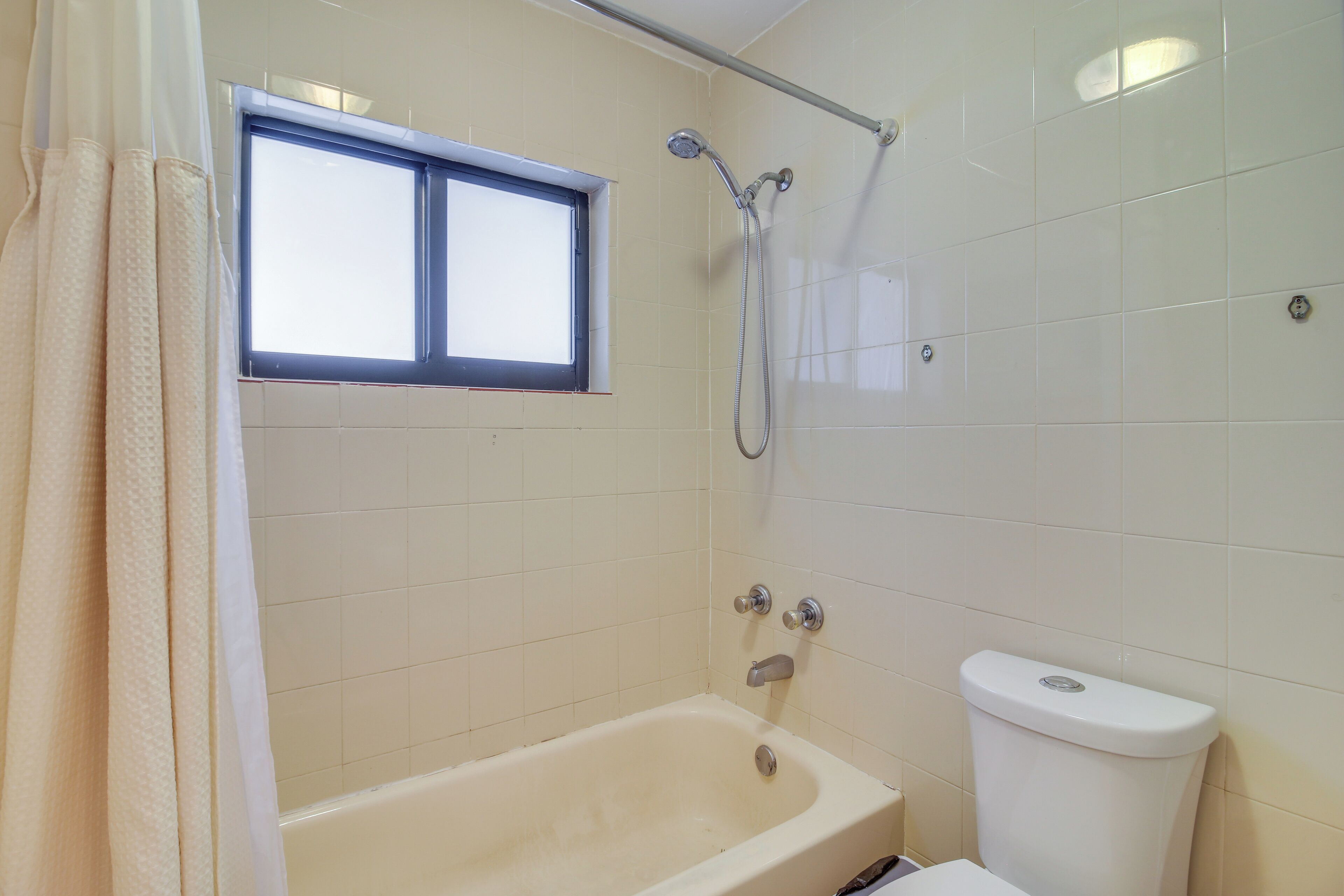 A bathroom with a bathtub, a shower, a toilet, and a window.
