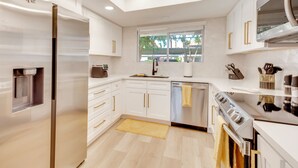 A modern kitchen with white cabinetry, stainless steel appliances, and a window providing natural light. - Patio & Pool Access! Mtn-view Palm Springs Escape (Palm Springs)