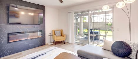 Una sala de estar moderna con chimenea, ventilador de techo, sofá y comedor.