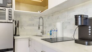 Eine Küche mit integriertem Mikrowellenherd, einer Kaffeemaschine und einem Wasserspender auf der Arbeitsfläche.
