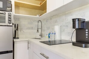 Eine Küche mit integriertem Mikrowellenherd, einer Kaffeemaschine und einem Wasserspender auf der Arbeitsfläche.