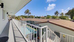 Ein Balkon mit Pool, weißen Geländern und einem Ziegeldach.