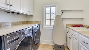A laundry area with a washing machine, an ironing board, and a sink. - Luxe Extended Stay w/ Swim Spa in Indian Land! (Fort Mill)