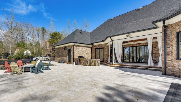 A patio with Adirondack chairs, a table, and a bar area with stools. - Luxe Extended Stay w/ Swim Spa in Indian Land! (Fort Mill)