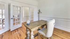 A dining area with a wooden table, a chair, and a lamp. - Luxe Extended Stay w/ Swim Spa in Indian Land! (Fort Mill)