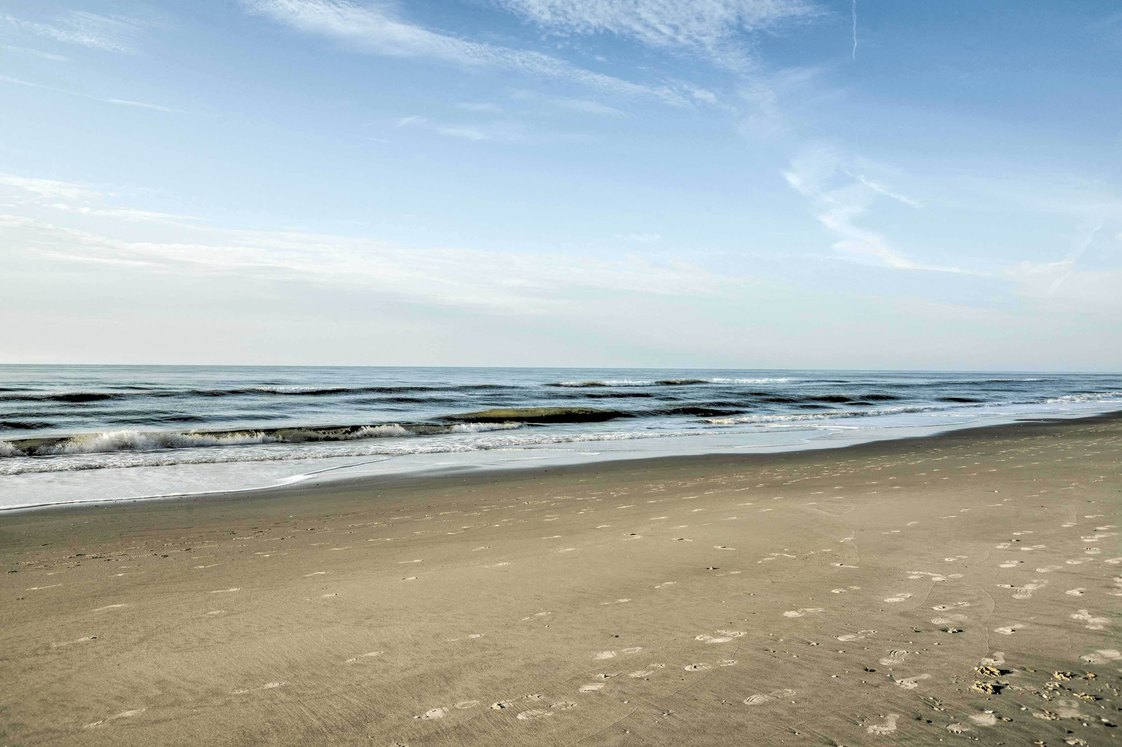 Ein Strand mit breitem Sandufer und sanften Wellen.