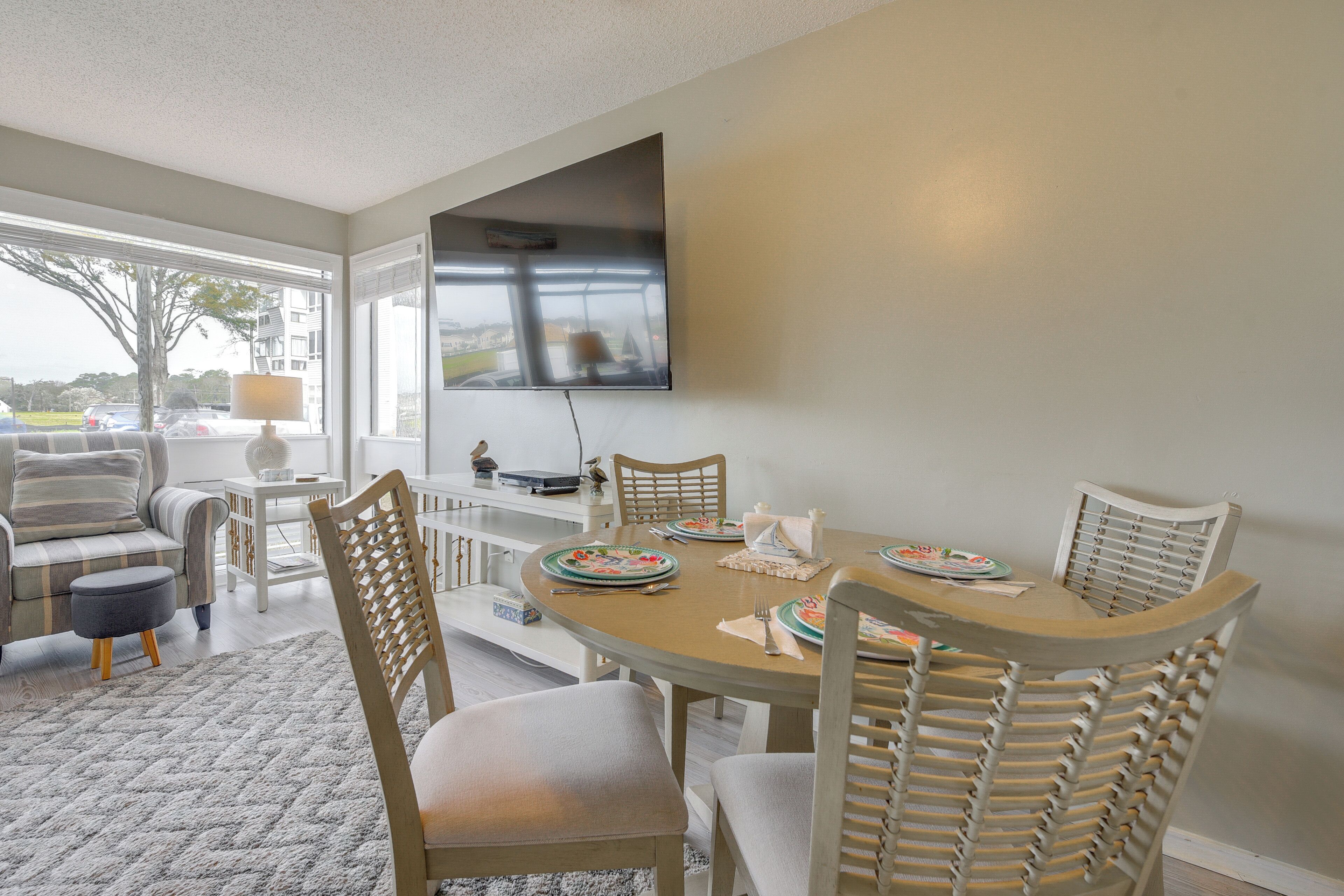 A dining area with a round table, chairs, and a flat-screen TV mounted on the wall.