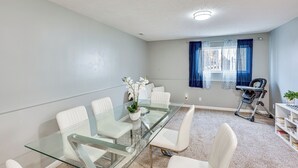 A modern meeting room with a glass table, white chairs, a baby rocker, and a bookshelf with books. - Private Yard & Patio: Spacious Retreat in Omaha! (Omaha)