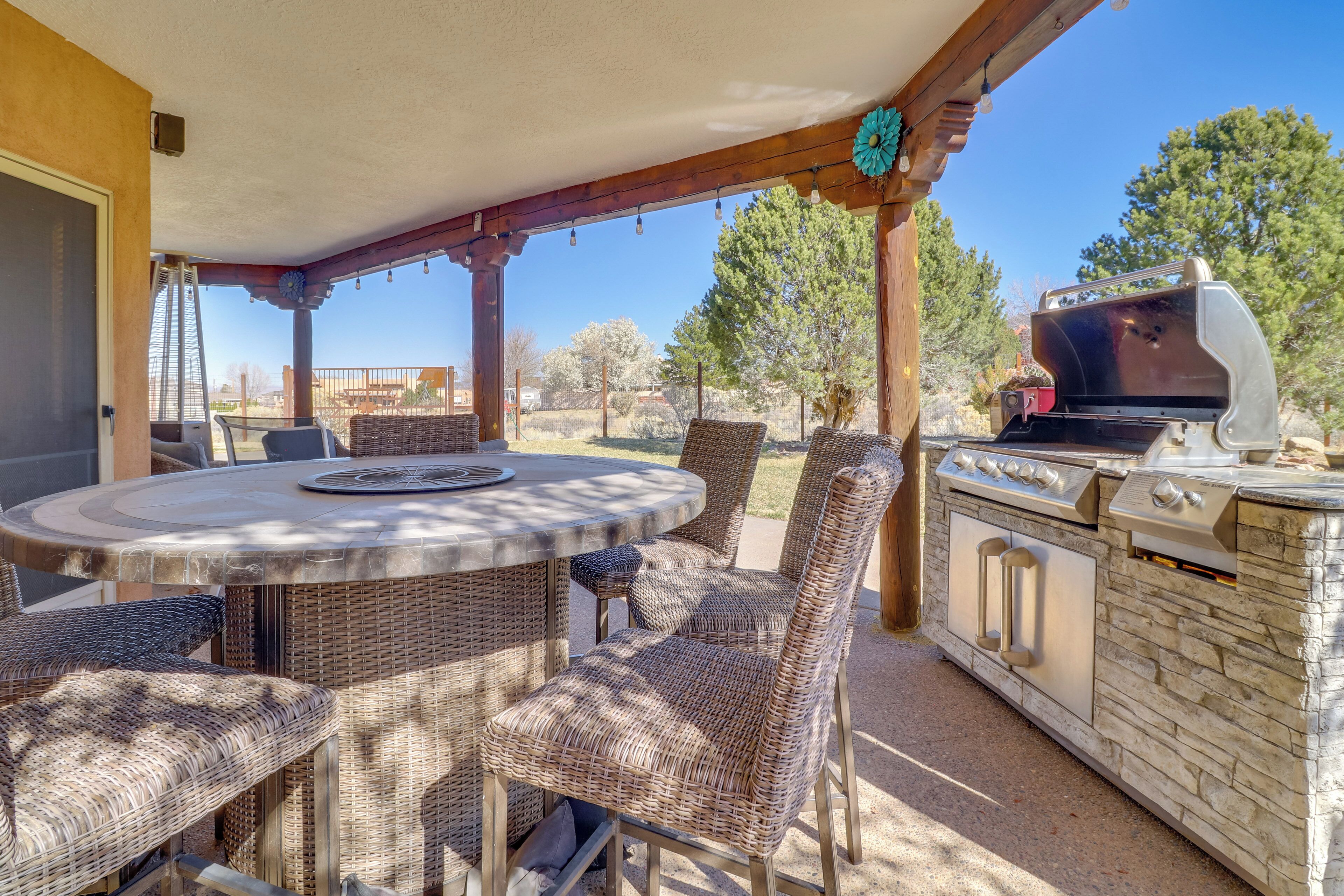 An outdoor patio with wicker furniture, a round table, and a built-in grill.