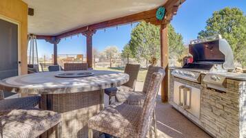 An outdoor patio with wicker furniture, a round table, and a built-in grill.