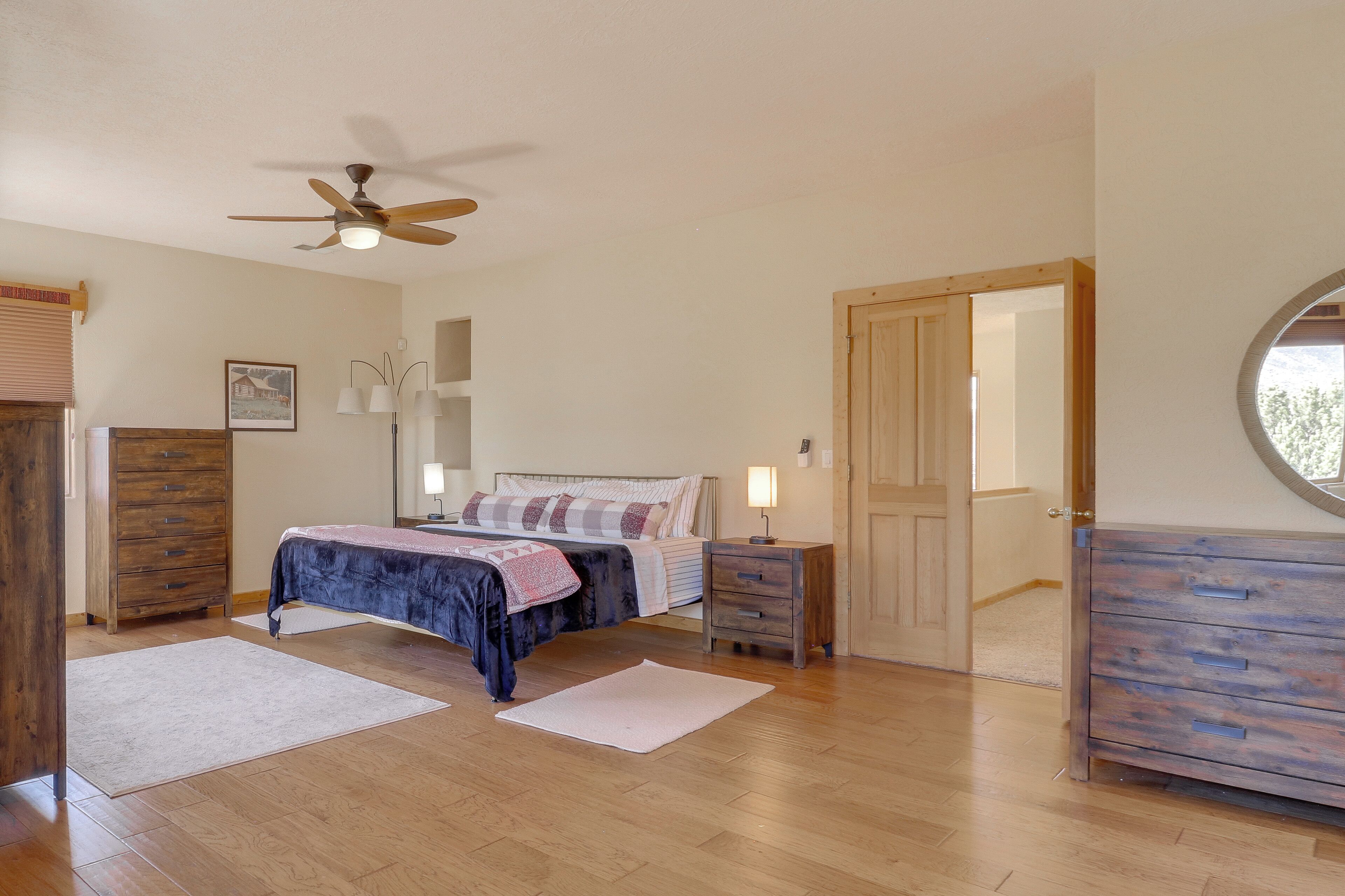 A bedroom with a bed, wooden dresser, nightstand, and ceiling fan.