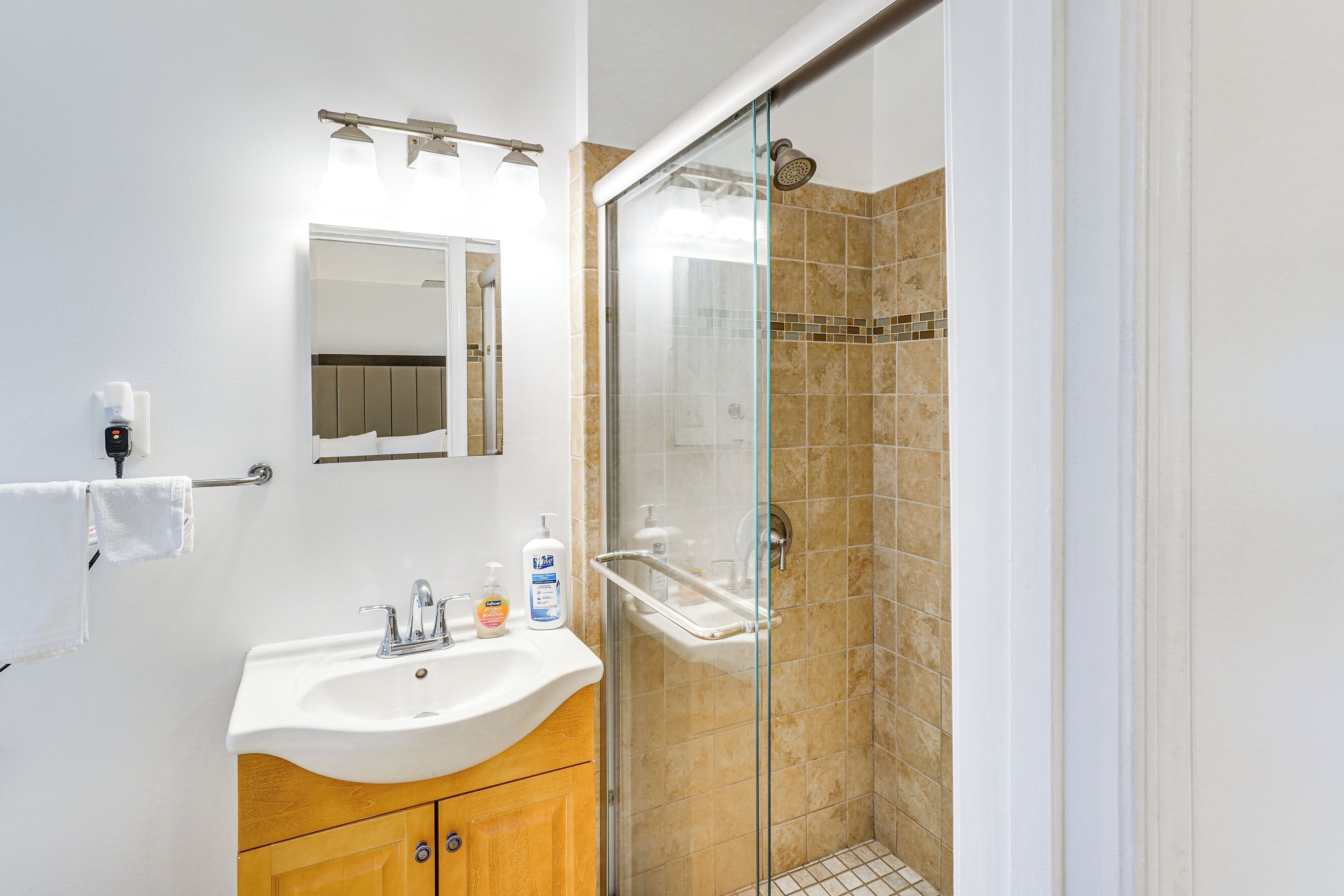 A bathroom with a sink, mirror, and shower.