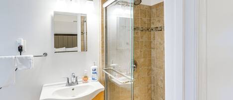 A bathroom with a sink, mirror, and shower.