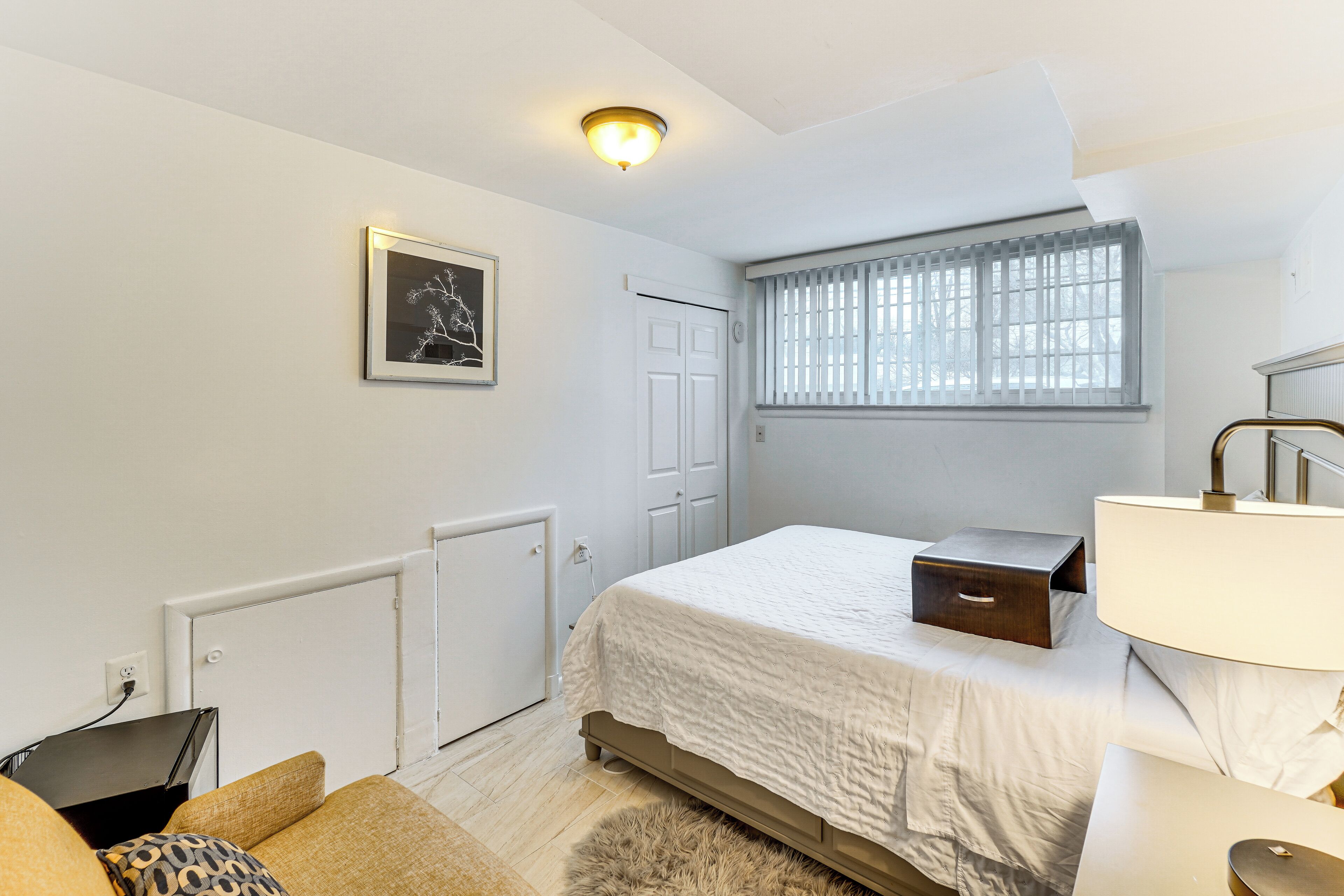Une chambre à coucher avec un lit, une table de chevet, une lampe et un tableau encadré au mur.