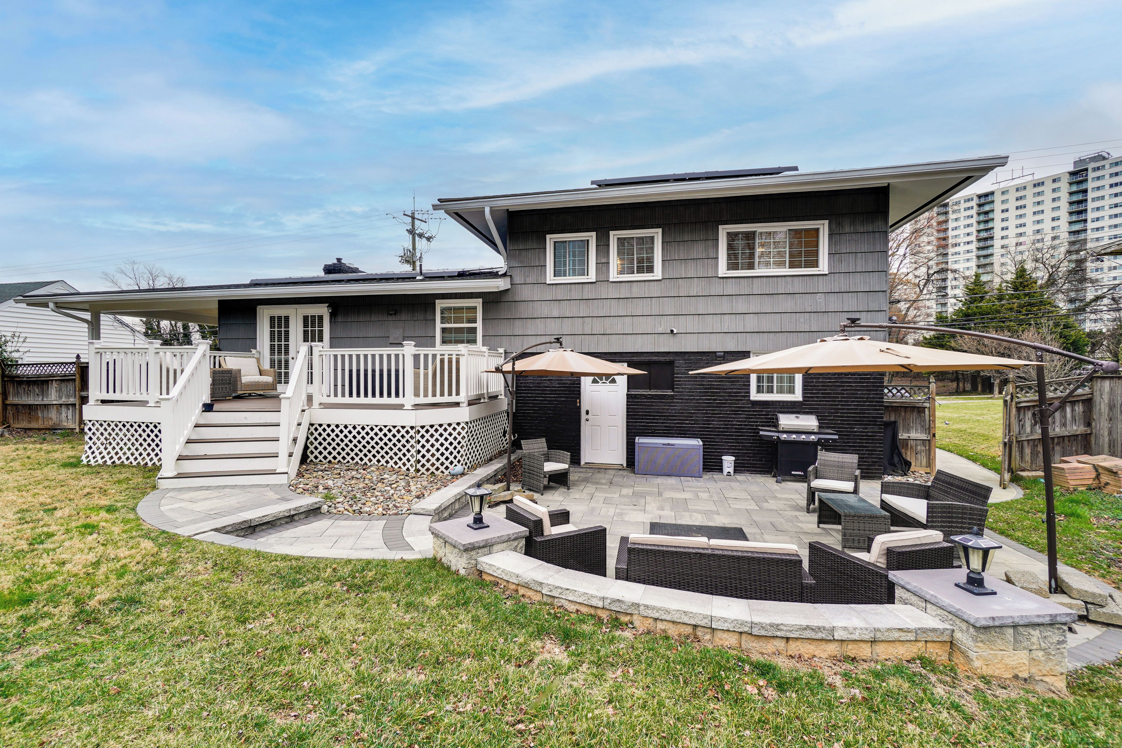 A two-story house with a covered patio, outdoor seating, and a fenced deck.