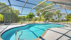 Una piscina con un recinto in vetro, circondata da un solarium e palme.