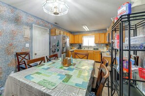 Une cuisine avec des meubles de rangement en bois, un réfrigérateur, une table à manger avec des chaises et un lustre.