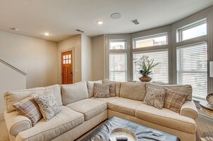 A living room with a beige sectional sofa, a coffee table, and a potted plant.