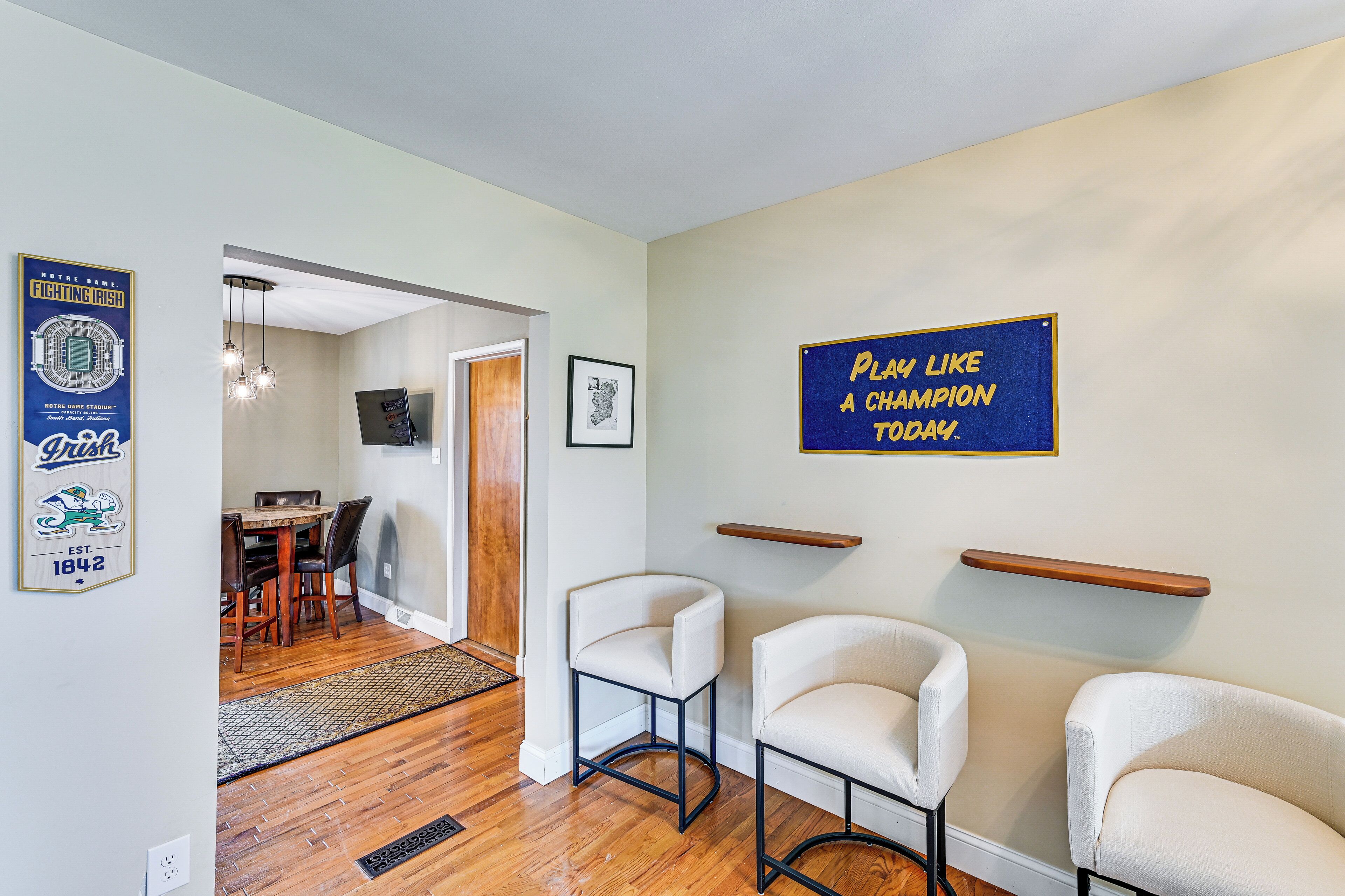 Un intérieur moderne comprenant un coin repas, deux chaises blanches, un panneau bleu affichant un message motivant et un tableau encadré au mur.